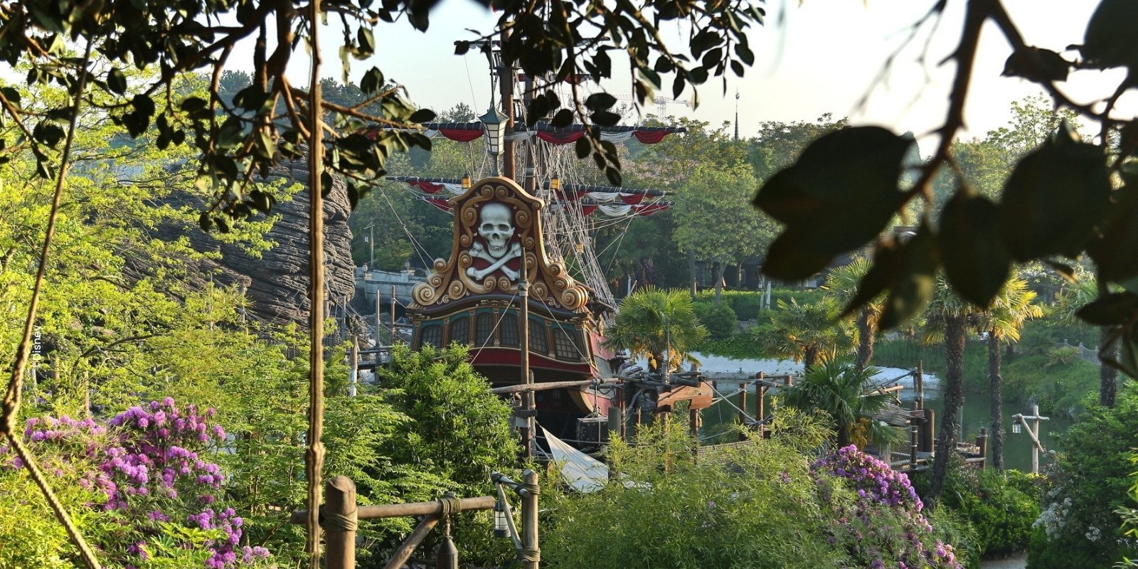 Piratenschiff zwischen Bäumen und rosa Blumen im Adventureland