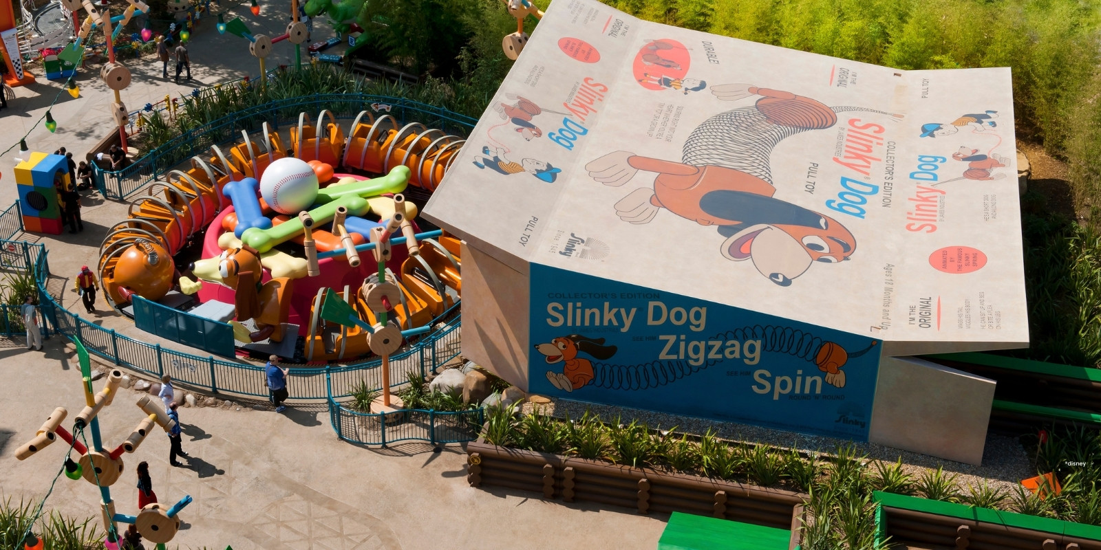 Schachtel mit braunem Spielzeughund Slinky Dog oben drauf und Slinky-Attraktion davor