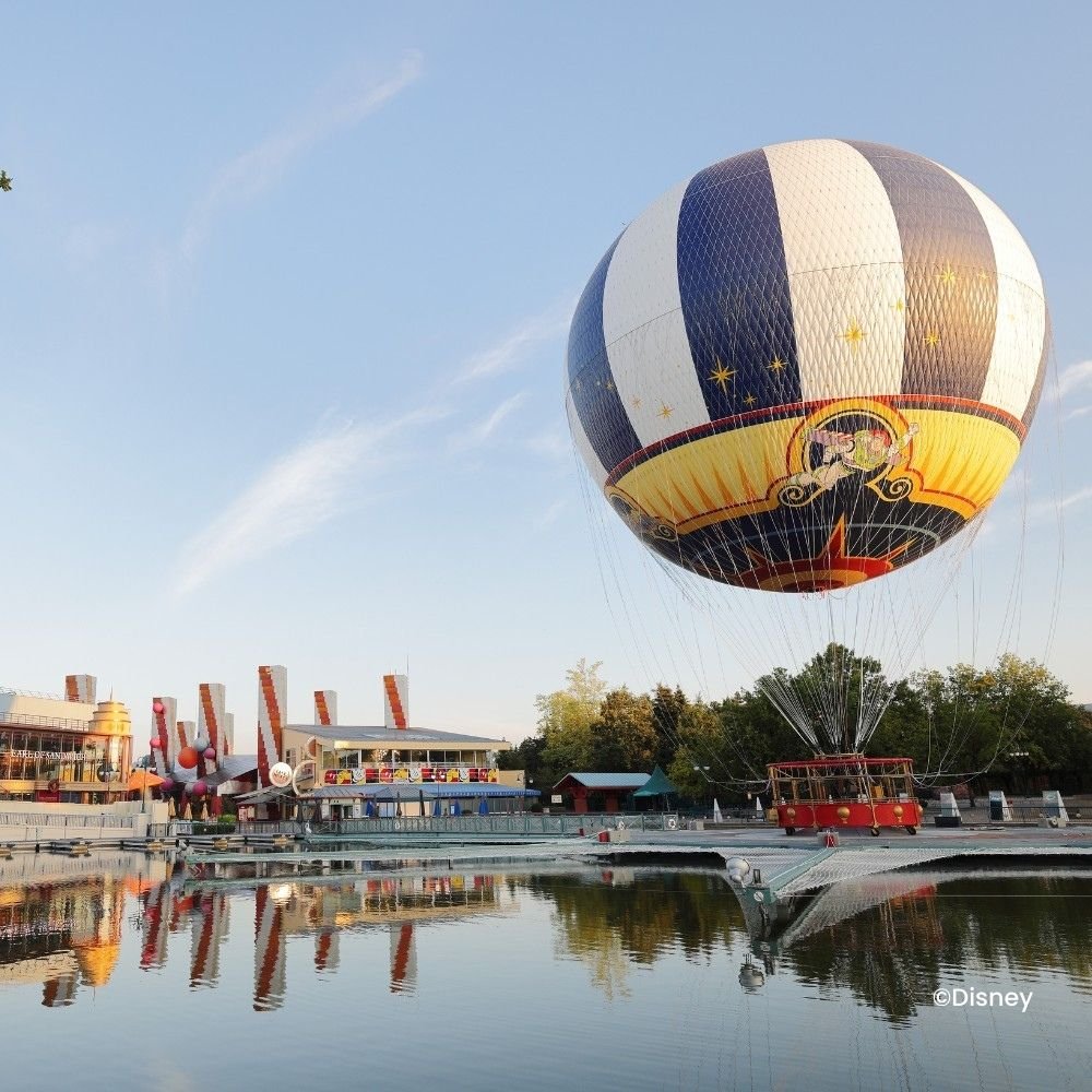 Lake Disney mit Blick auf den blau-weißen Ballon von Panoramagique und Disney Village®