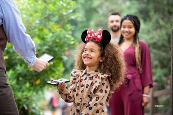 Disney app kaart scannen Mädchen mit Minnie-Mouse-Ohren lässt ihr Ticket in der App scannen