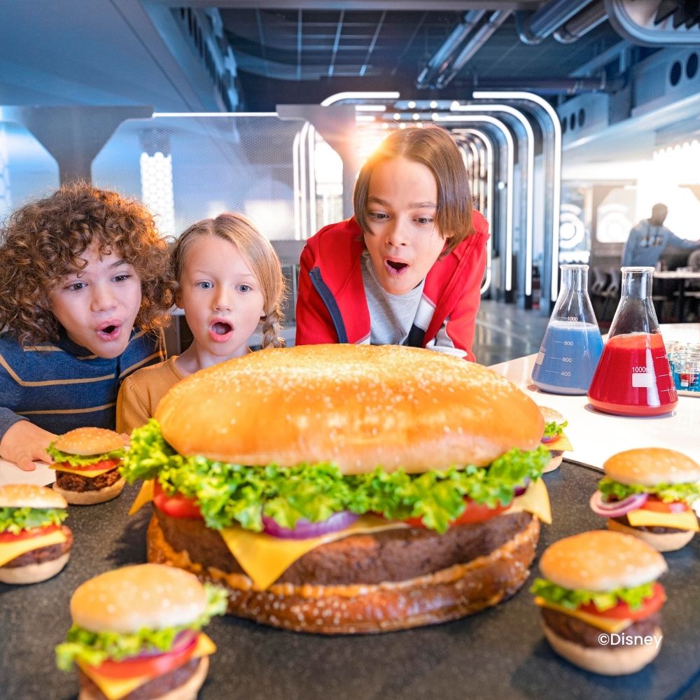 Kinder beobachten kleine und einen riesigen Hamburger