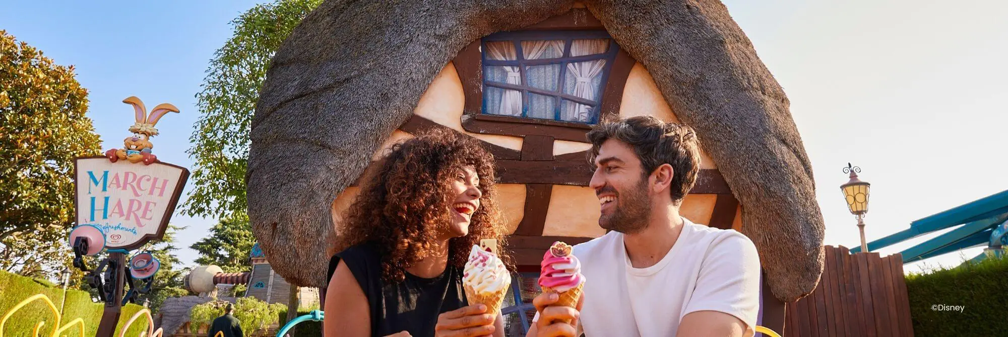 Menschen, die in der Sonne sitzen und ein Eis in einem der Disney® Parks genießen