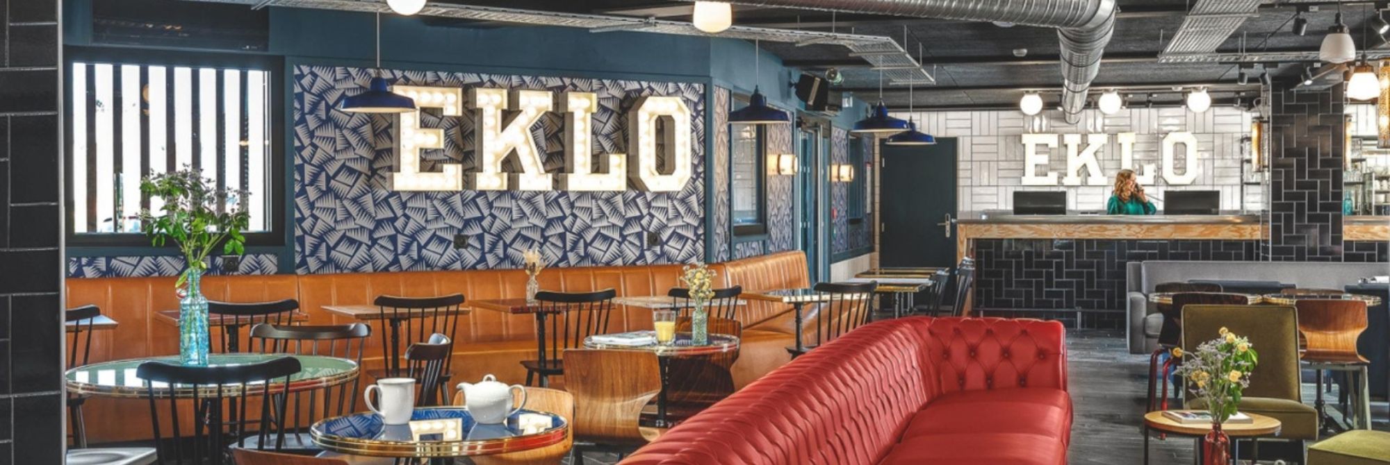 Eklo Hotel Marne la Vallée Bar mit rotem Ledersofa und EKLO Lampen an der Wand